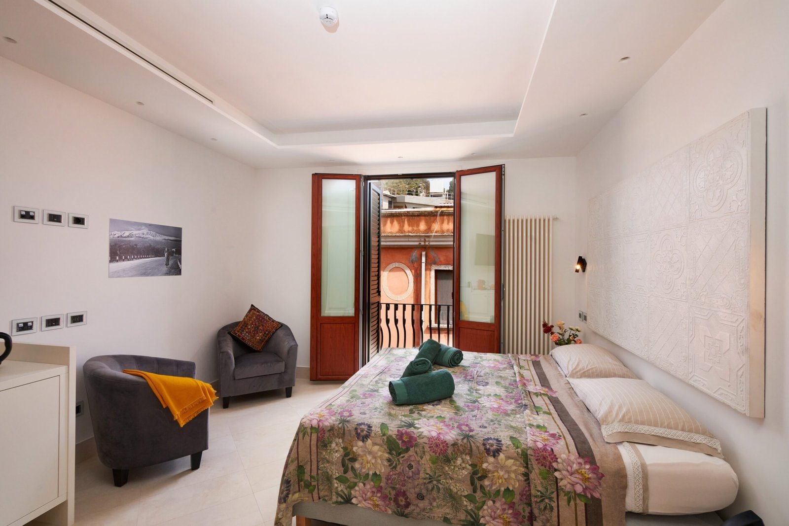 The Deluxe Suite, with two velvet armchairs and balcony doors thrown open