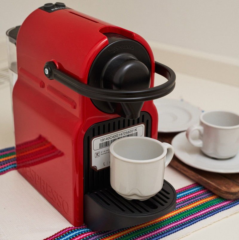 A red Nespresso machine with espresso cups