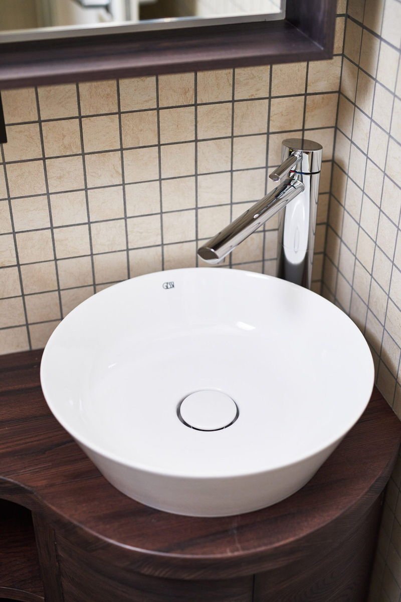 A round ceramic basin set on a walnut vanity
