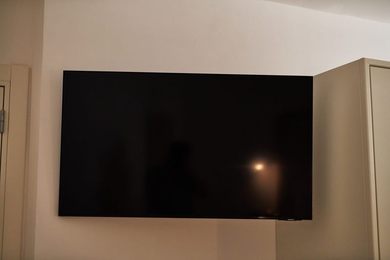 A large flat-screen television mounted on the bedroom wall